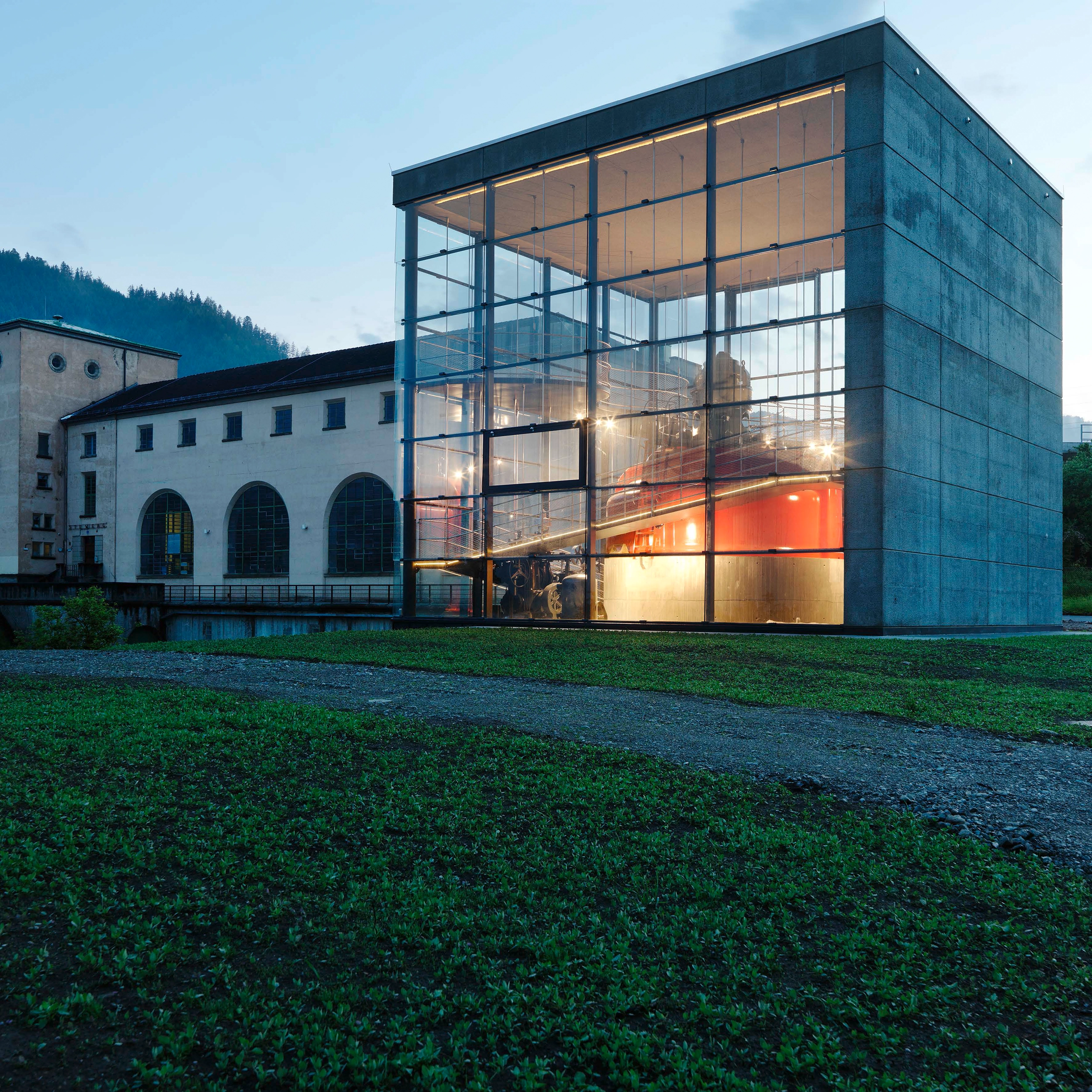 Ein Blick auf die Schauturbine Pernegg bei Dämmerung. Durch eine Glaskonstruktion sieht man die herrlich rote Turbine beleuchtet.